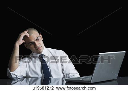 Businessman looking at a laptop and thinking View Large Photo Image Stock Image - Businessman looking at a laptop and thinking. Fotosearch