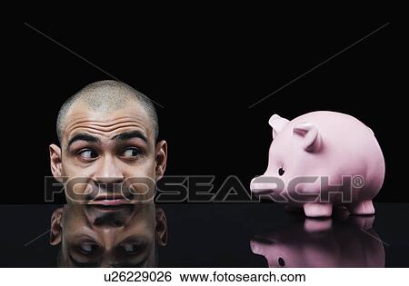 Stock Photograph - Businessman looking at a piggy bank. Fotosearch