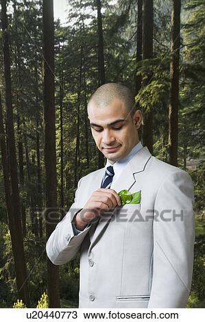 Stock Image - Businessman looking at a sapling in his pocket. Fotosearch