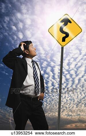 Picture - Businessman looking at a Zig Zag Road sign. Fotosearch