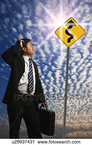 Businessman looking at a Zig Zag Road sign View Large Photo Image Stock Image - Businessman looking at a Zig Zag Road sign. Fotosearch