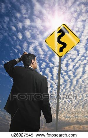 Businessman looking at a Zig Zag Road sign View Large Photo Image Stock Photography - Businessman looking at a Zig Zag Road sign. Fotosearch