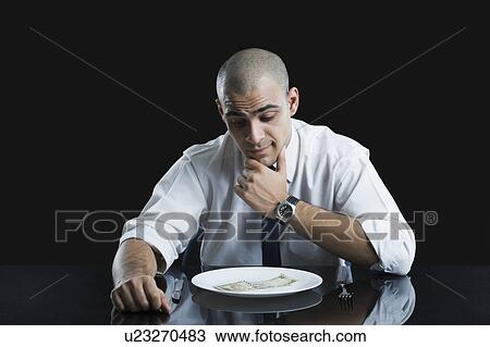 Businessman looking at money on a plate View Large Photo Image Stock Image - Businessman looking at money on a plate. Fotosearch
