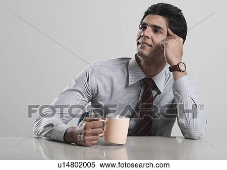 Businessman lost in thoughts while drinking coffee View Large Photo Image Stock Photography - Businessman lost in thoughts while drinking coffee. Fotosearch