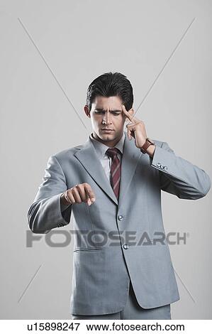 Businessman pointing forward with a finger on his temple View Large Photo Image Stock Photo - Businessman pointing forward with a finger on his temple. Fotosearch
