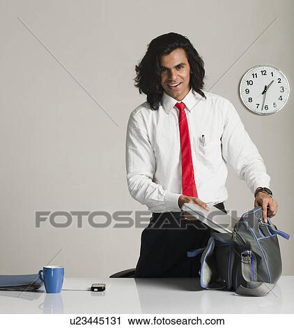 Stock Image - Businessman preparing to leave the office. Fotosearch