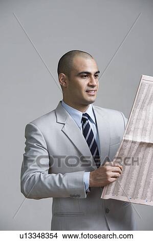 Picture - Businessman reading a newspaper and smiling. Fotosearch