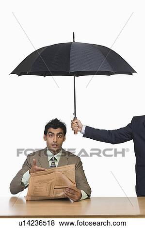 Businessman reading a newspaper under umbrella View Large Photo Image Stock Photo - Businessman reading a newspaper under umbrella. Fotosearch