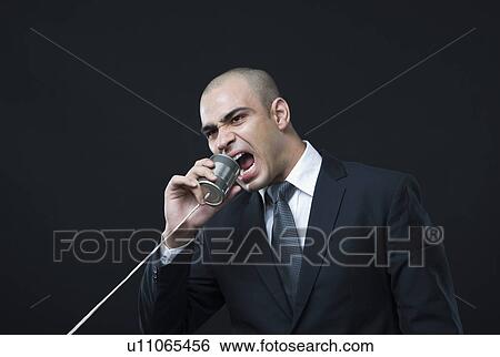 Businessman shouting on a tin can phone View Large Photo Image Stock Photograph - Businessman shouting on a tin can phone. Fotosearch