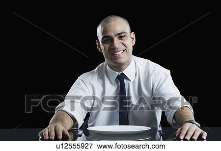 Businessman sitting at a dining table and smiling View Large Photo Image Stock Photo - Businessman sitting at a dining table and smiling. Fotosearch
