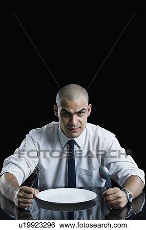 Businessman sitting at a dining table View Large Photo Image Stock Photograph - Businessman sitting at a dining table. Fotosearch