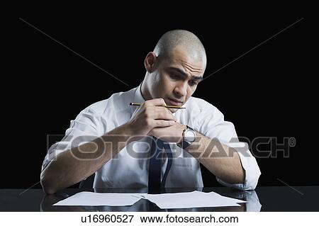 Stock Photo - Businessman sitting at a table and thinking. Fotosearch