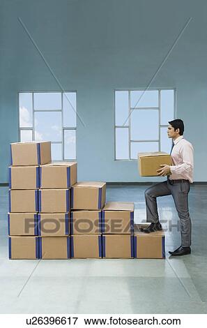 Stock Photo - Businessman stacking cardboard boxes in shape of rising bar graph. Fotosearch