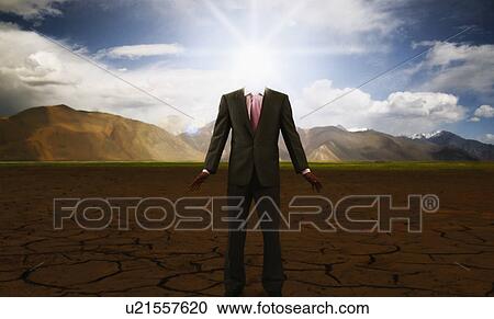 Stock Image - Businessman standing on a cracked landscape. Fotosearch