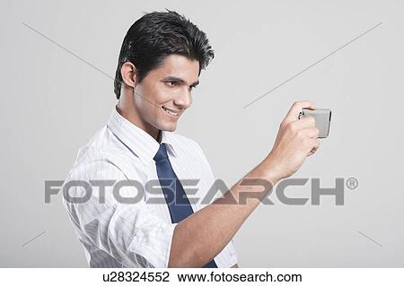 Businessman taking a picture with his mobile phone View Large Photo Image Stock Image - Businessman taking a picture with his mobile phone. Fotosearch
