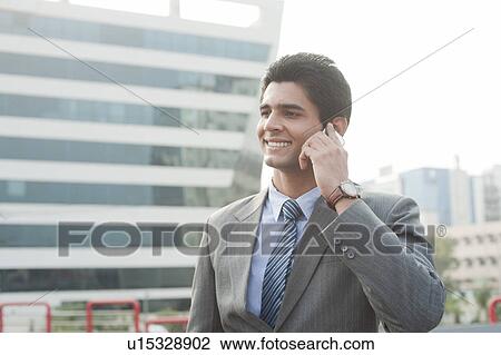 Stock Image - Businessman talking on a mobile phone, Gurgaon, Haryana, India. Fotosearch