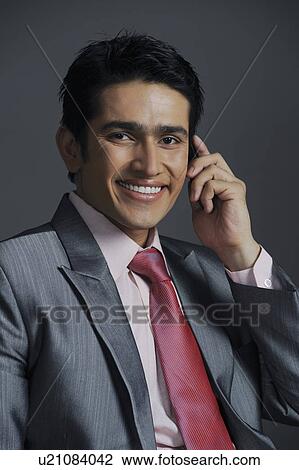 Stock Image - Businessman talking on a mobile phone and smiling. Fotosearch
