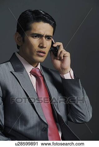 Stock Image - Businessman talking on a mobile phone and looking serious. Fotosearch