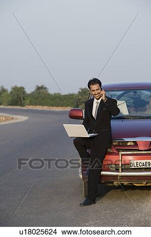 Businessman talking on the phone while using a laptop View Large Photo Image Picture - Businessman talking on the phone while using a laptop. Fotosearch