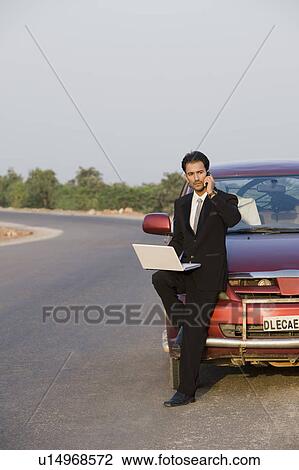 Businessman talking on the phone while using a laptop View Large Photo Image Stock Image - Businessman talking on the phone while using a laptop. Fotosearch
