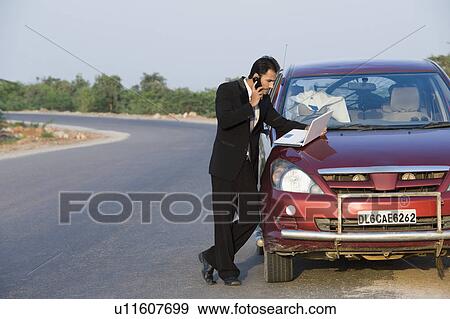 Businessman talking on the phone while using a laptop View Large Photo Image Stock Photo - Businessman talking on the phone while using a laptop. Fotosearch