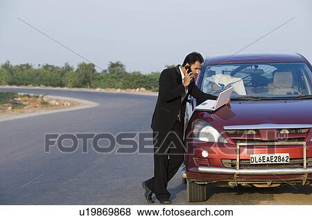 Stock Photo - Businessman talking on the phone while using a laptop. Fotosearch
