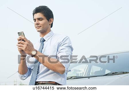 Businessman text messaging on a mobile phone, Gurgaon, Haryana, India View Large Photo Image Stock Photography - Businessman text messaging on a mobile phone, Gurgaon, Haryana, India. Fotosearch