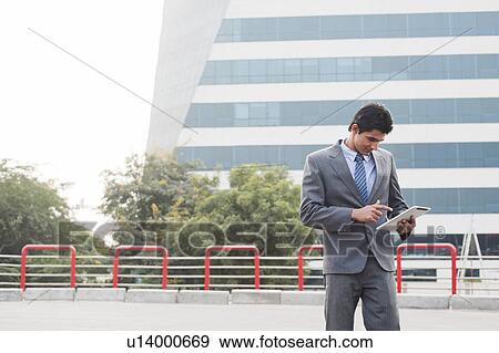 Businessman using a digital tablet, Gurgaon, Haryana, India View Large Photo Image Stock Photo - Businessman using a digital tablet, Gurgaon, Haryana, India. Fotosearch