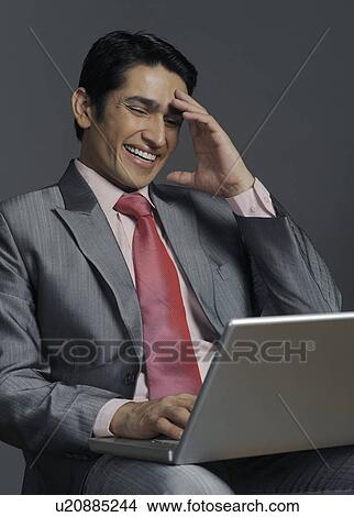 Picture - Businessman using a laptop and smiling. Fotosearch