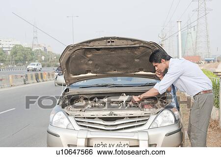 Stock Photograph - Businessman using a mobile phone near a broken down car, Gurgaon, Haryana, India. Fotosearch