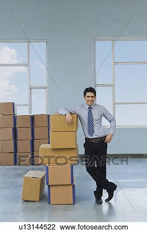 Businessman with cardboard boxes in a warehouse View Large Photo Image Stock Image - Businessman with cardboard boxes in a warehouse. Fotosearch