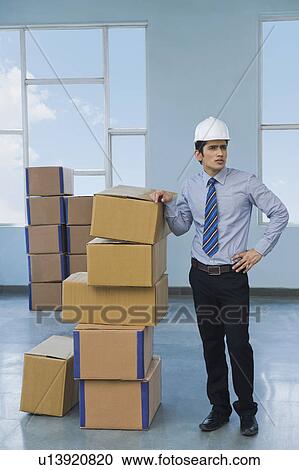 Stock Image - Businessman with cardboard boxes in a warehouse. Fotosearch