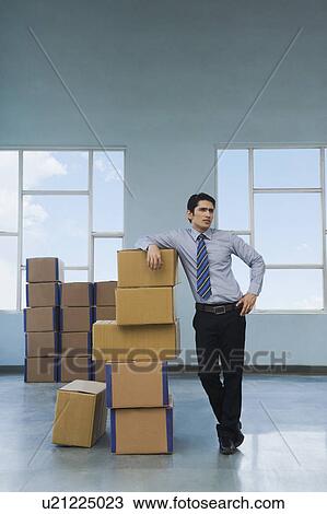 Businessman with cardboard boxes in a warehouse View Large Photo Image Stock Image - Businessman with cardboard boxes in a warehouse. Fotosearch