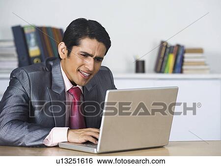 Stock Photograph - Businessman working on a laptop in an office. Fotosearch