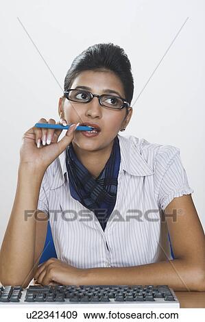 Businesswoman biting a pen and thinking View Large Photo Image Stock Photo - Businesswoman biting a pen and thinking. Fotosearch