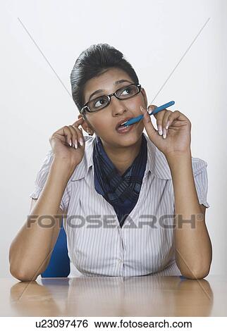 Businesswoman biting a pen and thinking View Large Photo Image Stock Photograph - Businesswoman biting a pen and thinking. Fotosearch