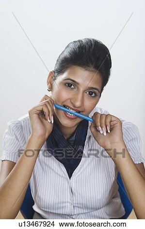 Picture - Businesswoman biting a pen. Fotosearch
