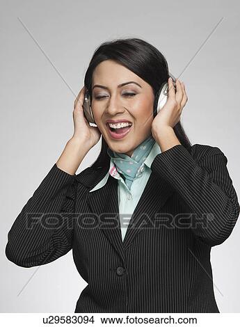 Picture - Businesswoman enjoying music on headphones. Fotosearch