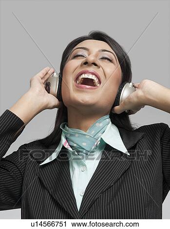 Stock Image - Businesswoman enjoying music on headphones. Fotosearch