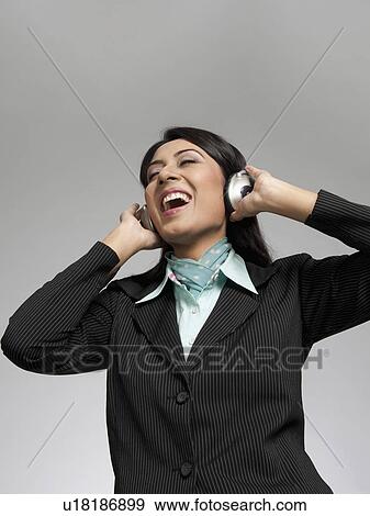 Stock Photo - Businesswoman enjoying music on headphones. Fotosearch
