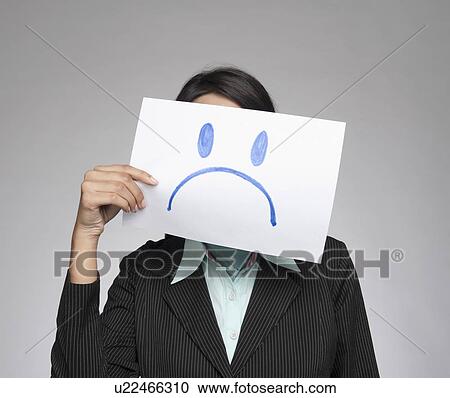 Businesswoman holding a sad face in front of her face View Large Photo Image Stock Image - Businesswoman holding a sad face in front of her face. Fotosearch
