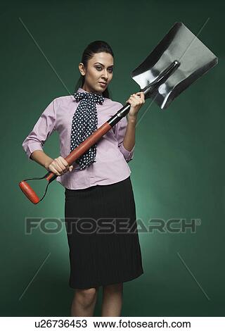 Stock Image - Businesswoman holding a shovel. Fotosearch
