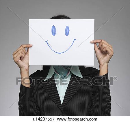 Stock Photo - Businesswoman holding a smiley face in front of her face. Fotosearch