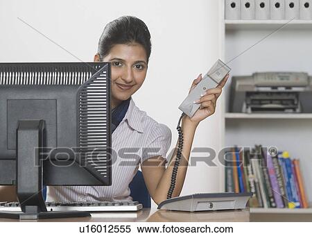 Stock Photography - Businesswoman holding a telephone receiver. Fotosearch