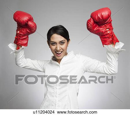 Businesswoman in boxing gloves cheering with arms raised View Large Photo Image Picture - Businesswoman in boxing gloves cheering with arms raised. Fotosearch