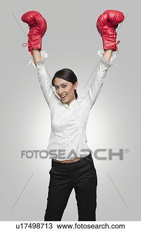 Businesswoman in boxing gloves cheering with arms raised View Large Photo Image Stock Image - Businesswoman in boxing gloves cheering with arms raised. Fotosearch