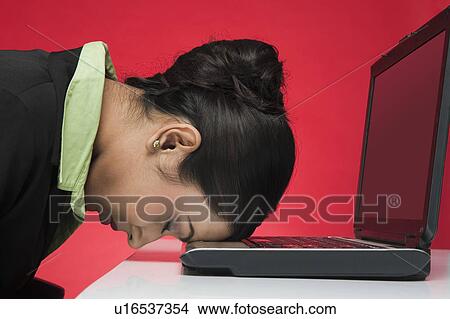 Picture - Businesswoman in front of a laptop with head down. Fotosearch