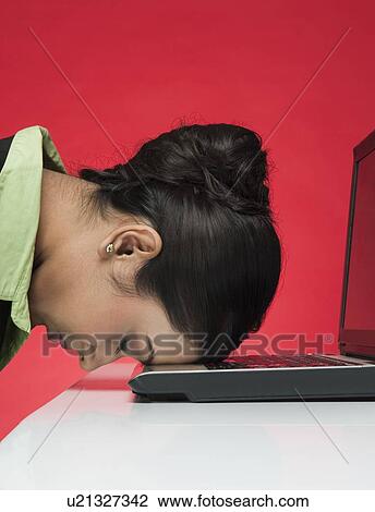 Stock Image - Businesswoman in front of a laptop with head down. Fotosearch