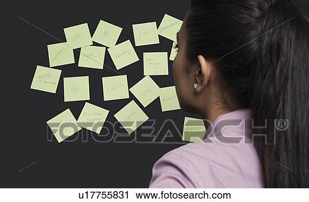 Businesswoman looking at adhesive notes on a board View Large Photo Image Stock Image - Businesswoman looking at adhesive notes on a board. Fotosearch