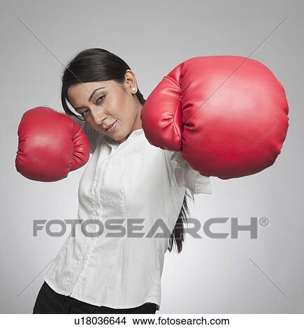 Picture - Businesswoman punching with boxing gloves. Fotosearch